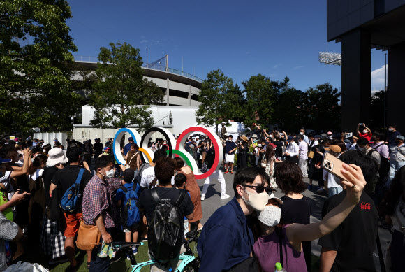 23일 도쿄올림픽 개회식이 열리는 일본 도쿄 신주쿠 올림픽 스타디움 앞 오륜기 조형물에 모인 도쿄 시민들이 기념사진을 찍고 있다. 연합뉴스