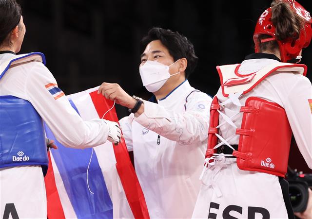 태국 태권도를 이끌어 온 최영석 감독이 24일 일본 마쿠하리 메세 A홀에서 열린 도쿄올림픽 여자 태권도 49㎏급 결승에서 승리한 파니팍 선수에게 태국 국기를 전달하고 있다. 최 감독 밑에서 태국 태권도는 2004년 아테네 올림픽부터 2016년 리우 올림픽까지 연속 메달(은 2, 동 3)을 획득했다. 태국이 태권도 올림픽에서 금메달을 차지한 것은 이번이 처음이다. 2021.7.25 뉴스1