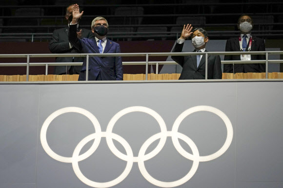 23일(현지시간) 일본 도쿄 올림픽 개막식에서 손을 흔드는 토마스 바흐 국제올림픽위원회 위원장(왼쪽). AP