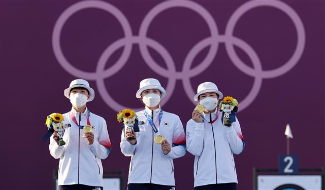 한국 여자 양궁 대표팀 안산(왼쪽부터), 장민희, 강채영 선수가 25일 일본 도쿄 유메노시마 공원 양궁장에서 열린 여자 양궁 단체전에서 금메달을 딴 뒤 시상식에 올라 금메달을 들어보이고 있다. 도쿄 올림픽사진공동취재단