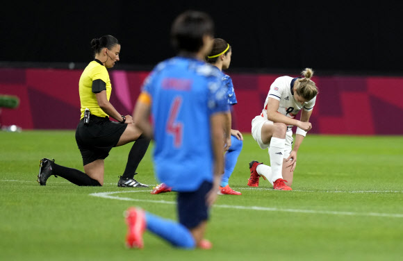 지난 24일 도쿄올림픽 여자축구 E조 2차전에서 일본과 영국 선수들이 러시아 심판 아나스타샤 포스토보이토바(왼쪽)와 무릎 꿇기를 하고 있다. 도쿄 AP 연합뉴스