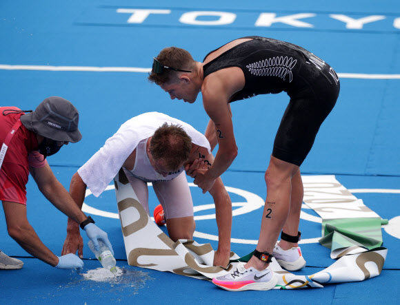 26일 오전 열린 도쿄올림픽 트라이애슬론 경기에서 구토하는 선수들을 돕는 동료와 스태프. 로이터 연합