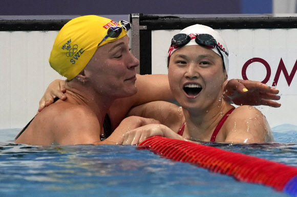 마가렛 맥닐(오른쪽) 선수가 2020 도쿄올림픽 여자 접영 100m에서 우승하자 전 세계신기록 보유자인 스웨덴의 사라 스조스트롬 선수의 축하를 받고 있다. AP 연합뉴스