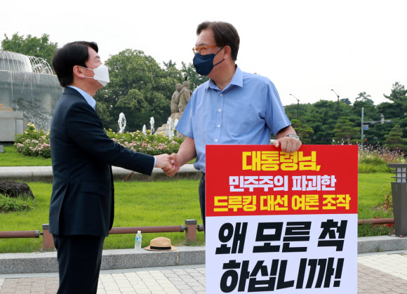 국민의당 안철수 대표(왼쪽)가 29일 오전 서울 종로구 청와대 사랑채 앞에서 ‘드루킹 댓글 사건’ 관련 1인 시위를 벌이고 있는 국민의힘 정진석 의원을 지지 방문해 악수하고 있다. 2021.7.29  연합뉴스