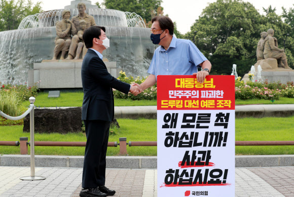 국민의당 안철수 대표(왼쪽)가 29일 오전 서울 종로구 청와대 사랑채 앞에서 ‘드루킹 댓글 사건’ 관련 1인 시위를 벌이고 있는 국민의힘 정진석 의원을 지지 방문해 악수하고 있다. 2021.7.29  연합뉴스