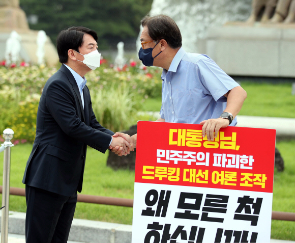 안철수 국민의당 대표가 29일 오전 서울 종로구 청와대 앞 분수대에서 ‘드루킹 사건’ 문재인 대통령의 사과를 촉구하는 1인 시위 펼치는 정진석 국민의힘 의원을 찾아 악수를 나누고 있다. 2021.7.29   김명국 선임기자 daunso@seoul.co.kr