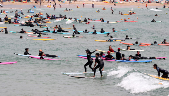 폭염이 이어진 30일 오후 부산 송정해수욕장을 찾은 서퍼들이 서핑을 즐기고 있다. 2021.7.30  연합뉴스