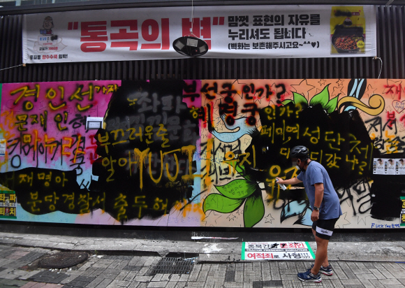 1일 서울 종로의 한 서점 담벼락에그려진 쥴리벽화에 한 시민이 자신의 의견을 담은 메시지를 덧칠하고 있다. 2021.8.1  박지환 기자 popocar@seoul.co.kr