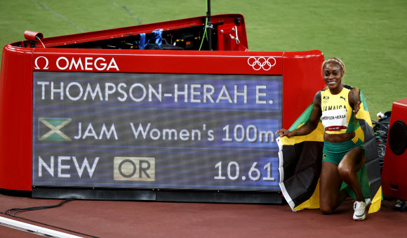 2016년 리우올림픽에 이어 육상 여자 100m 2연패에 성공한 톰프슨은 자신의 기록이 표시된 전광판 앞에서 자메이카 국기를 몸에 두르고 밝게 웃고 있다. 도쿄 로이터 연합뉴스