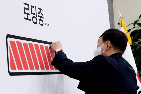 국민의힘 대선 예비후보인 윤석열 전 검찰총장이 2일 오전 서울 여의도 국회에서 이준석 국민의힘 대표와 김기현 원내대표 및 최고위원들을 예방해 회의장 배경막에 있는 ‘로딩중’ 그래프에 배터리 스티커를 붙이고 있다.2021. 8. 2 김명국 선임기자 daunso@seoul.co.kr