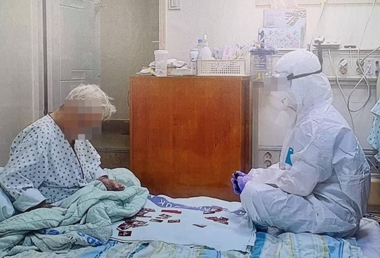 격리된 요양병원에서 방호복을 입은 의료진과 할머니가 화투를 치고 있다. SNS 캡처
