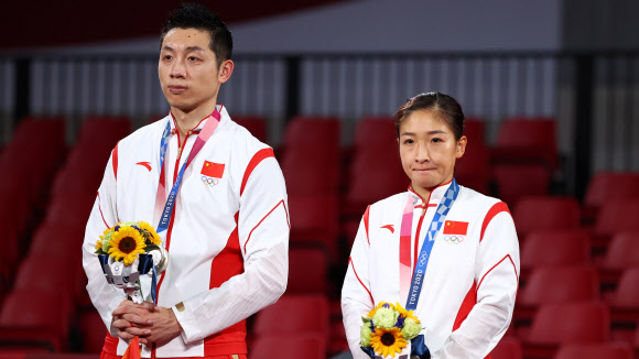 지난달 26일 도쿄올림픽 탁구 혼합복식 결승에서 일본에 져 은메달을 딴 중국 대표팀 쉬신(왼쪽)과 류스원이 침울한 표정으로 시상대에 서 있다. 이들은 금메달을 못 딴 데 대해 국민들에게 눈물로 사죄를 해야 했다. 도쿄 로이터 연합뉴스