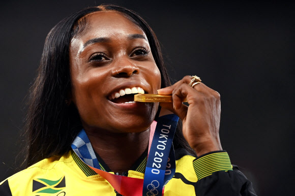 일레인 톰프슨헤라(자메이카)가 지난 3일 도쿄 올림픽 스타디움에서 이어진 2020 도쿄올림픽 육상 여자 200m를 우승하며 두 대회 연속 100m와 200m 2관왕을 차지하며 최초의 더블더블을 달성한 뒤 금메달을 깨무는 퍼포먼스를 하고 있다. 도쿄 AFP 연합뉴스 