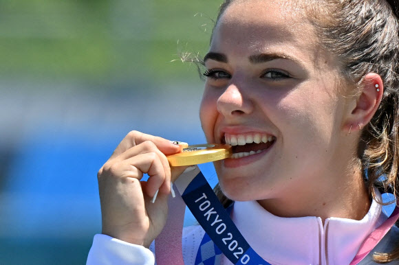 2020 도쿄 올림픽 여성 카누 200m에서 금메달을 딴 미국의 네빈 해리슨 선수가 5일 메달을 깨물어보고 있다. AFP 연합뉴스.