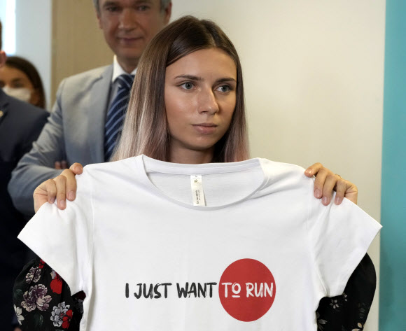 일본을 떠나 지난 4일(현지시간) 폴란드에 도착한 벨라루스 육상 선수 크리스치나 치마노우스카야가 다음날 바르샤바에서 진행된 기자회견에 입장하면서 ‘난 달리고 싶을 뿐’이라고 새긴 티셔츠를 들어 보이고 있다. 바르샤바 AP 연합뉴스