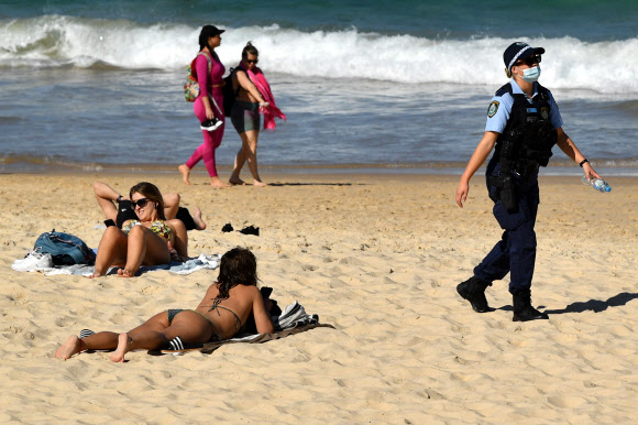 뉴사우스웨일스(NSW) 경찰이 11일(현지시간) 호주 시드니 본다이 비치에서 일광욕을 즐기는 시민들 사이를 순찰하고 있다. EPA 연합뉴스