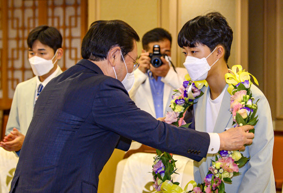 11일 광주시청 비즈니스룸에서 열린 2020 도쿄올림픽 광주선수단 환영행사에서 이용섭 광주시장이 양궁 3관왕에 오른 안산 선수에게 꽃목걸이를 걸어주고 있다. 2021.8.11 연합뉴스