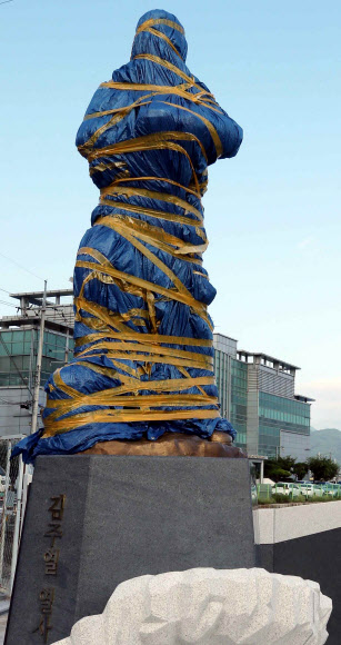 경남 창원시 마산합포구 중앙부두에 3·15 부정선거를 규탄하는 시위에 참여했다 얼굴에 최루탄이 박혀 숨진 채 마산만에 떠오른 김주열 열사 동상이 동상 추모판 문구를 둘러싸고 지역 민주운동 단체가 대립하면서 완성되고도 비닐과 테이프로 꽁꽁 감겨 한 달째 서 있다. 사진은 지난 11일 오후 촬영. 2021.8.12  연합뉴스