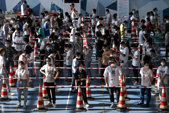 지난 5일 중국 중부 후베이성 우한에 있는 한 기업체 체육관에서 코로나 바이러스 검사를 받기 위해 장사진을 치고 있는 직원들. 우한 AFP 연합뉴스