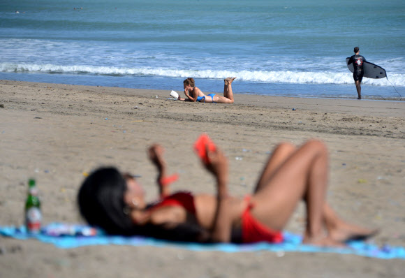해변에서 휴식을 취하는 사람들이 14일(현지시간) 인도네시아 휴양지 발리의 쿠타 해변에서 일광욕을 즐기고 있다. AFP 연합뉴스