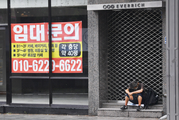 비가 내린 8월의 어느 날, 서울 종로의 임대 현수막이 붙은 텅 빈 상점 앞에 노숙인이 지친 표정으로 앉아 있다. 장기적인 코로나19의 영향으로 폐업률이 늘어 가고 있는 가운데 폐업의 위기에 몰린 자영업자들의 시름이 날로 깊어지고 있다.<br>박지환 기자 popocar@seoul.co.kr