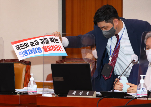 25일 서울 여의도 국회에서 열린 법제사법위원회 전체회의에서 법사위 관계자가 국민의힘 의원들이 퇴장한 뒤 남겨져 있던 ‘언론중재법’ 반대 손팻말을 정리하고 있다. 2021.8.25  연합뉴스