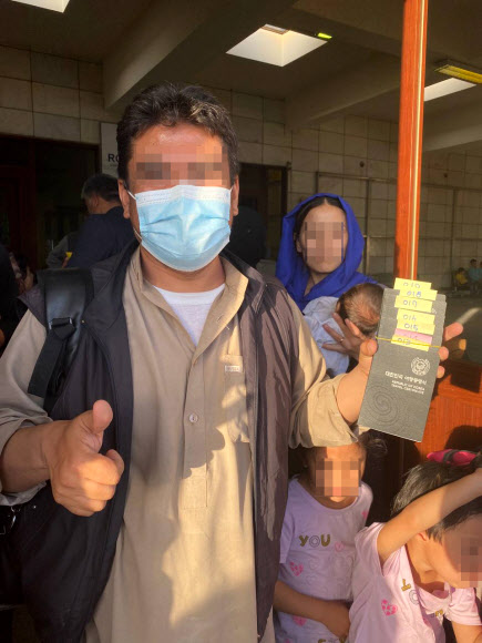 한국 정부와 협력한 아프가니스탄인이 카불공항에 도착한 공군 수송기에 탑승하기 전 외교부가 발행한 여행증명서를 들고 기뻐하고 있다. 2021.8.25  외교부 제공