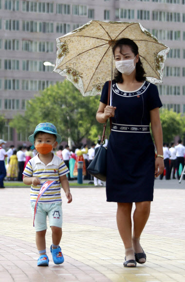 25일 북한 평양에서 코로나19 확산을 막기 위해 마스크를 쓴 여성들이 한복을 입고 거리를 걷고 있다. AP 연합뉴스