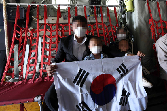 한국으로 이송될 아프간 현지 조력자와 가족들이 25일 아프가니스탄 카불공항에서 공군 C-130J 수송기에 탑승해 태극기를 펼쳐 보이고 있다. 2021.8.26  공군 제공