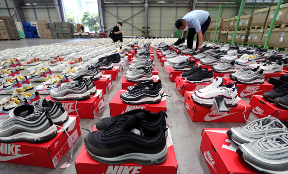 26일 부산 강서구 부산세관신항지정장치장에서 직원이 해외 유명 브랜드 제품을 본떠 만든 중국산 ‘짝퉁’ 운동화 압수품을 공개하고 있다. 부산본부세관은 나이키, 구찌, 발렌시아가 등 해외 유명 브랜드 위조 상표 운동화 2천 켤레(정품 시가 17억 원어치)를 밀수입해 ‘000 스마트스토어’ 등 유명 오픈마켓에서 정품인 것처럼 판매한 일당 3명을 붙잡아 1명을 구속했다고 밝혔다. 2021.8.26  연합뉴스