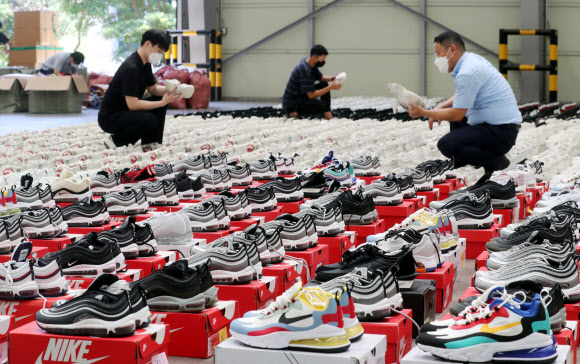 26일 부산 강서구 부산세관신항지정장치장에서 직원이 해외 유명 브랜드 제품을 본떠 만든 중국산 ‘짝퉁’ 운동화 압수품을 공개하고 있다. 부산본부세관은 나이키, 구찌, 발렌시아가 등 해외 유명 브랜드 위조 상표 운동화 2천 켤레(정품 시가 17억 원어치)를 밀수입해 ‘000 스마트스토어’ 등 유명 오픈마켓에서 정품인 것처럼 판매한 일당 3명을 붙잡아 1명을 구속했다고 밝혔다. 2021.8.26  연합뉴스