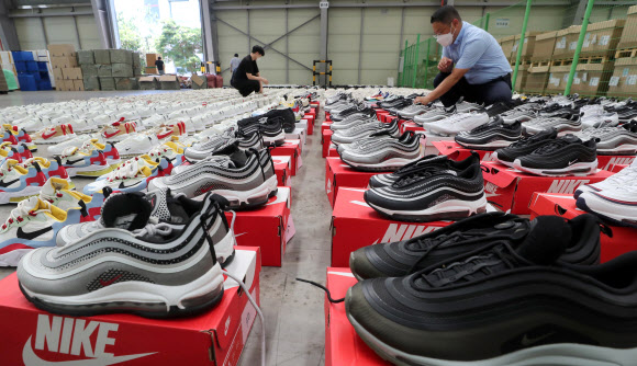 26일 부산 강서구 부산세관신항지정장치장에서 직원이 해외 유명 브랜드 제품을 본떠 만든 중국산 ‘짝퉁’ 운동화 압수품을 공개하고 있다. 부산본부세관은 나이키, 구찌, 발렌시아가 등 해외 유명 브랜드 위조 상표 운동화 2천 켤레(정품 시가 17억 원어치)를 밀수입해 ‘000 스마트스토어’ 등 유명 오픈마켓에서 정품인 것처럼 판매한 일당 3명을 붙잡아 1명을 구속했다고 밝혔다. 2021.8.26  연합뉴스