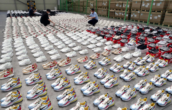 26일 부산 강서구 부산세관신항지정장치장에서 직원이 해외 유명 브랜드 제품을 본떠 만든 중국산 ‘짝퉁’ 운동화 압수품을 공개하고 있다. 부산본부세관은 나이키, 구찌, 발렌시아가 등 해외 유명 브랜드 위조 상표 운동화 2천 켤레(정품 시가 17억 원어치)를 밀수입해 ‘000 스마트스토어’ 등 유명 오픈마켓에서 정품인 것처럼 판매한 일당 3명을 붙잡아 1명을 구속했다고 밝혔다. 2021.8.26  연합뉴스