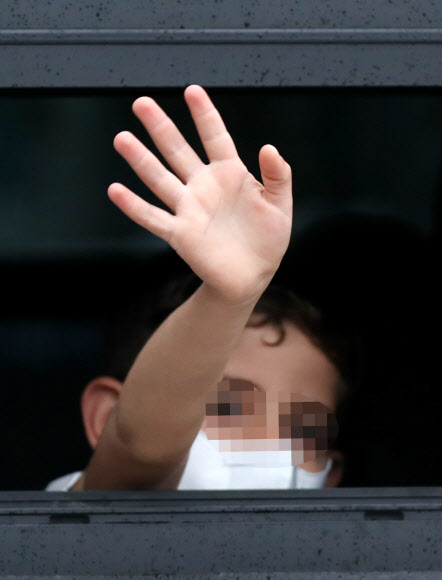 과거 한국을 도왔던 아프가니스탄 협력자 가족 중 한 어린이가 27일 오전 임시격리시설인 경기도 김포의 한 호텔에서 버스를 타고 충북 진천으로 출발하면서 시설 관계자와 취재진을 향해 손을 흔들고 있다. 이들은 진천 국가공무원인재개발원에서 6주간 생활하며 한국 사회 적응을 위한 교육을 받을 예정이다. 2021.8.27  연합뉴스