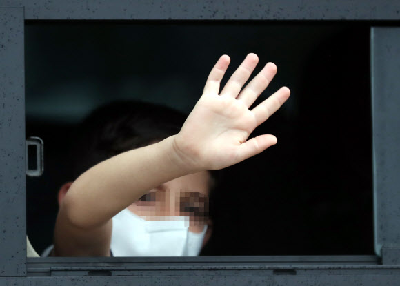과거 한국을 도왔던 아프가니스탄 협력자 가족 중 한 어린이가 27일 오전 임시격리시설인 경기도 김포의 한 호텔에서 버스를 타고 충북 진천으로 출발하면서 시설 관계자와 취재진을 향해 손을 흔들고 있다. 이들은 진천 국가공무원인재개발원에서 6주간 생활하며 한국 사회 적응을 위한 교육을 받을 예정이다. 2021.8.27  연합뉴스