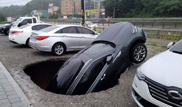 1일 오전 충남 당진시 한 공터에서 싱크홀이 발생해 차량 1대 차체 절반이 구멍에 빠졌다. 이날 당진에는 폭우가 쏟아졌다. 연합뉴스 