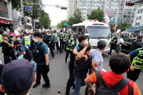 민주노총 조합원들이 6일 오전 서울 종로경찰서 앞 도로가 양경수 전국민주노동조합총연맹(민주노총) 위원장의 검찰 송치에 반대하며 도로에 진입하자 경찰이 이를 막으며 양 위원장이 탄 호송차를 안내하고 있다. 2021.9.6  연합뉴스