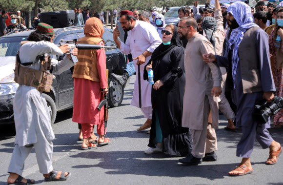 아프가니스탄 수도 카불의 파키스탄 대사관 인근에서 7일(현지시간) 아프간인들이 구호를 외치며 파키스탄의 자국 문제 개입에 항의하는 시위를 벌이자 탈레반 대원이 이들에게 총을 겨누고 있다. 2021-09-08 카불 로이터 연합뉴스
