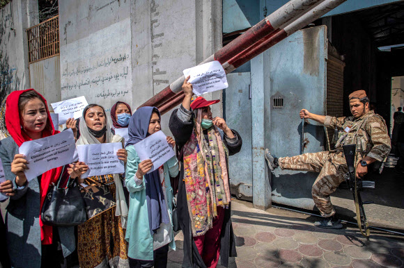 아프가니스탄 여성들이 19일(현지시간) 카불의 옛 여성부 청사 앞에서 탈레반 대원이 지켜보는 가운데 여성 권리 증진을 요구하는 시위를 벌이고 있다. AFP 연합뉴스