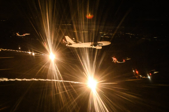 문재인 대통령이 국군유해와 함께 탑승한 공군1호기가 23일 대한민국 영공으로 들어서자 공군 F-15K 전투기가 호위 비행하며 플레어를 발사하고 있다. 2021.9.24   국방부 제공