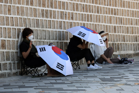 신종 코로나바이러스 감염증(코로나19) 확산 방지를 위해 도심내 집회금지가 이어지고 있는 가운데 26일 오전 서울 종로구 광화문광장 인근에서 사랑제일교회 신도들이 예배하고 있다.  사랑제일교회는 사회적 거리두기 4단계로 대면 예배가 금지된 이후에도 매주 일요일 대면 예배를 강행해 2차례의 운영 중단 명령을 받았으나 이를 무시하고 대면 예배를 계속한 끝에 지난달 19일 성북구로부터 시설폐쇄 명령을 받았다. 2021.9.26  연합뉴스