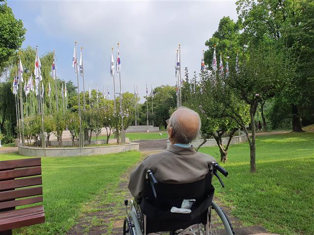 용산2가동 주민센터가 지난 11일 김칠수(가명) 노인의 쓰레기집 청소에 나섰다. 집 청소 덕분에 나들이를 나온 김 노인이 휠체어에 앉아 있는 모습.