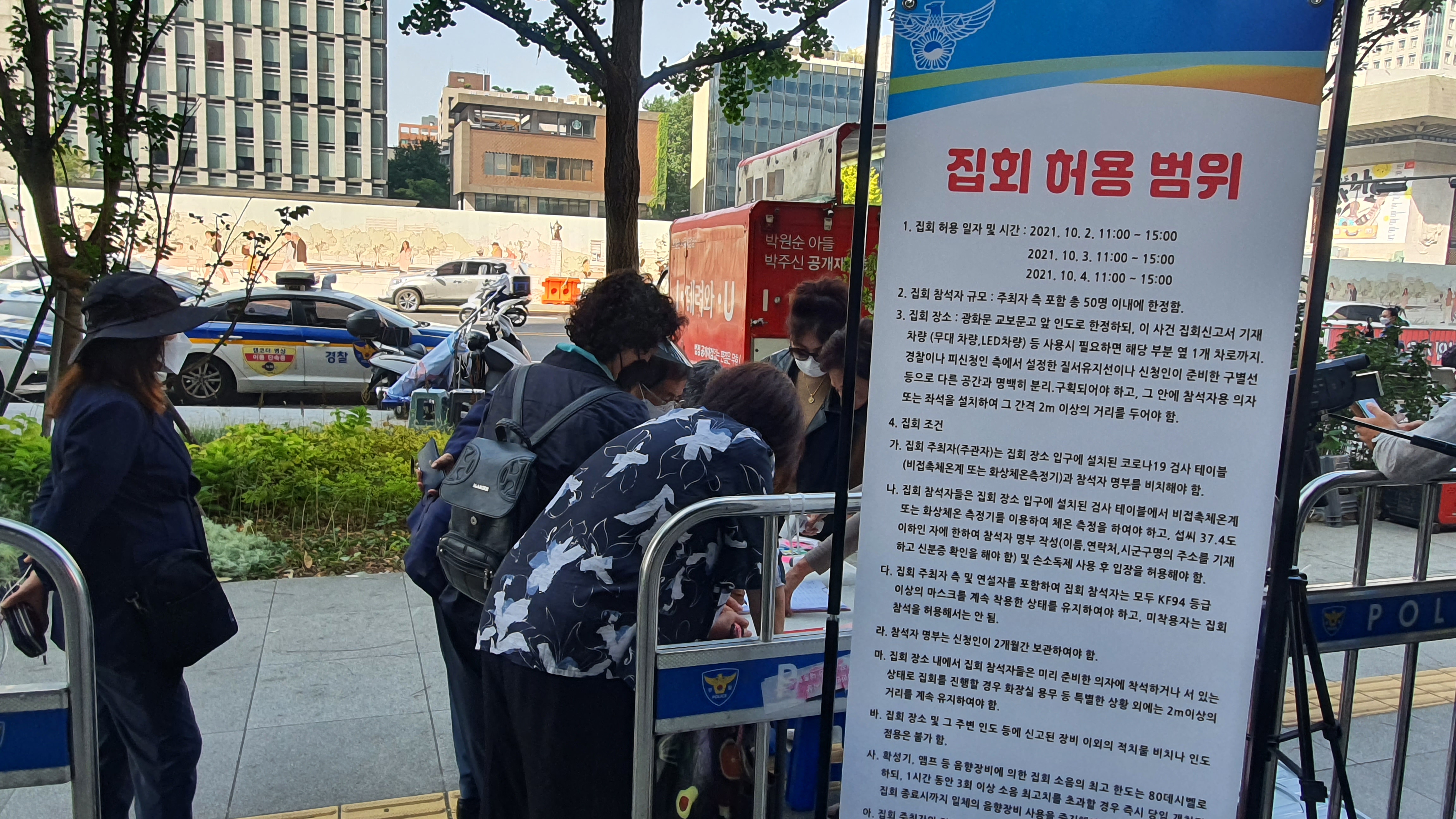 개천절인 3일 서울 종로구 광화문 교보빌딩 앞에서 열린 집회에 입장하려는 참가자들이 출입 명부를 쓰고 있다. 법원은 50인에 한해 집회를 일부 허용했다. 손지민 기자 sjm@soeul.co.kr