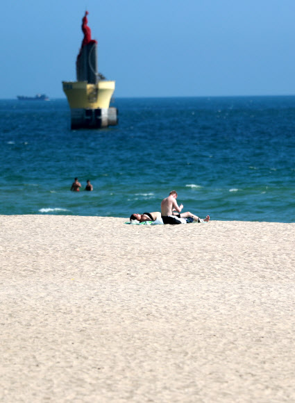 낮 기온이 30도에 육박하는 등 남부지방에 늦더위가 이어지고 있는 5일 오후 부산 해운대 해수욕장에 외국인들이 해변에서 휴식을 취하고 있다. 2021.10.5  연합뉴스