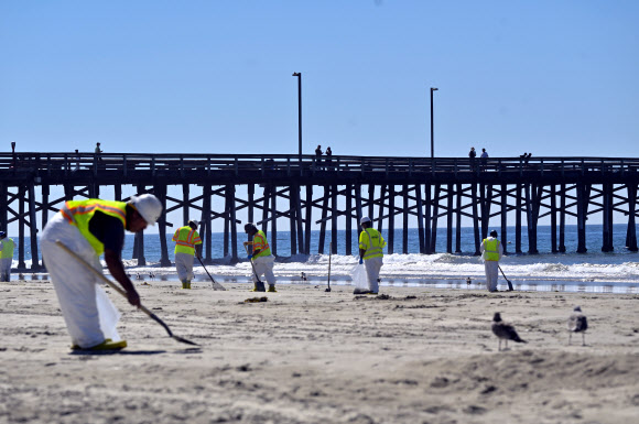 5일(현지시간) 미국 캘리포니아주뉴포트비치 항구 남쪽 해변에서 방재 요원들이 기름 제거 작업을 벌이고 있다.  AP 연합뉴스