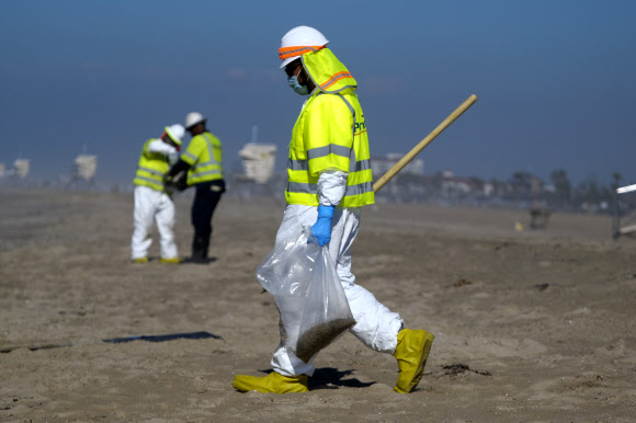 5일(현지시간) 미국 캘리포니아주 헌팅턴비치에서 방재 요원이 기름 제거 작업을 벌이고 있다.  AP 연합뉴스