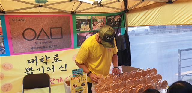6일 서울 종로구 대학로의 한 설탕 뽑기(달고나) 가게가 영업을 준비하고 있다. 천막 뒤편에는 넷플릭스 드라마 ‘오징어 게임’에 등장한 명함 사진이 걸려 있다. 김주연 기자 justina@seoul.co.kr
