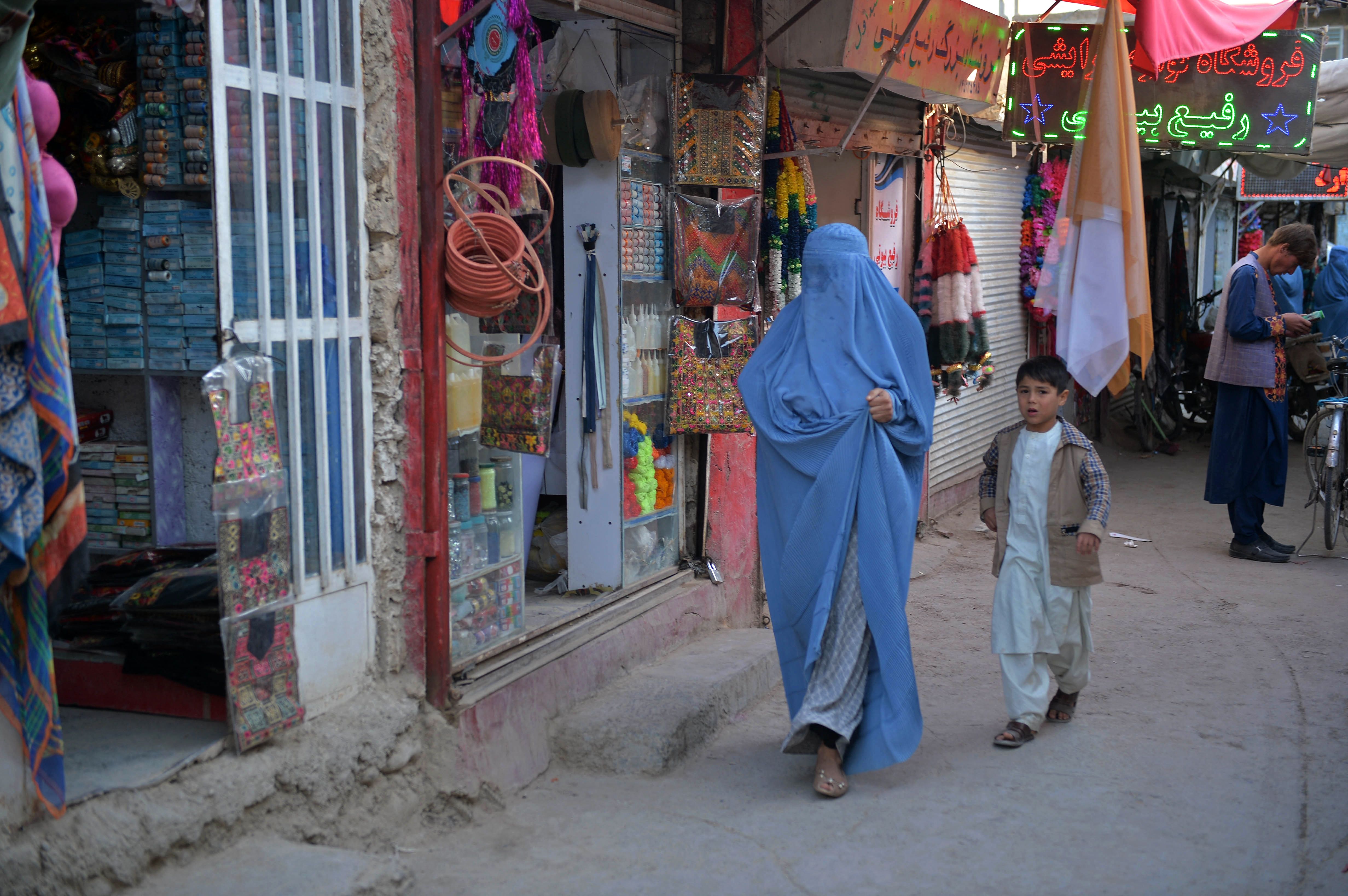 부르카를 입은 아프가니스탄 여성이 소년과 함께 16일(현지시간) 아프간 북서부 바드기스주 칼라에나우의 시장을 걷고 있다. 칼라에나우 AFP 연합뉴스 