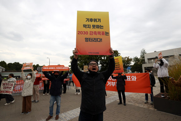 18일 탄소중립위원회 전체회의가 열린 노들섬 다목적홀 건너편에서 기후위기비상행동 등 환경단체 회원들이 회의를 마치고 나오는 정부 관계자들을 향해 감축 시나리오 전면 재수립 등을 요구하며 항의하고 있다. 2021.10.18  연합뉴스