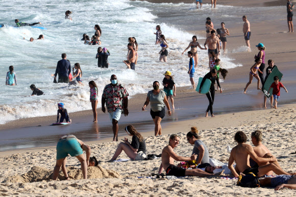 코로나19로 인한 봉쇄령이 해제되자 18일(현지시간) 호주 시드니 쿠지 비치에서 시민들이 물놀이와 일광욕을 즐기고 있다. 로이터 연합뉴스
